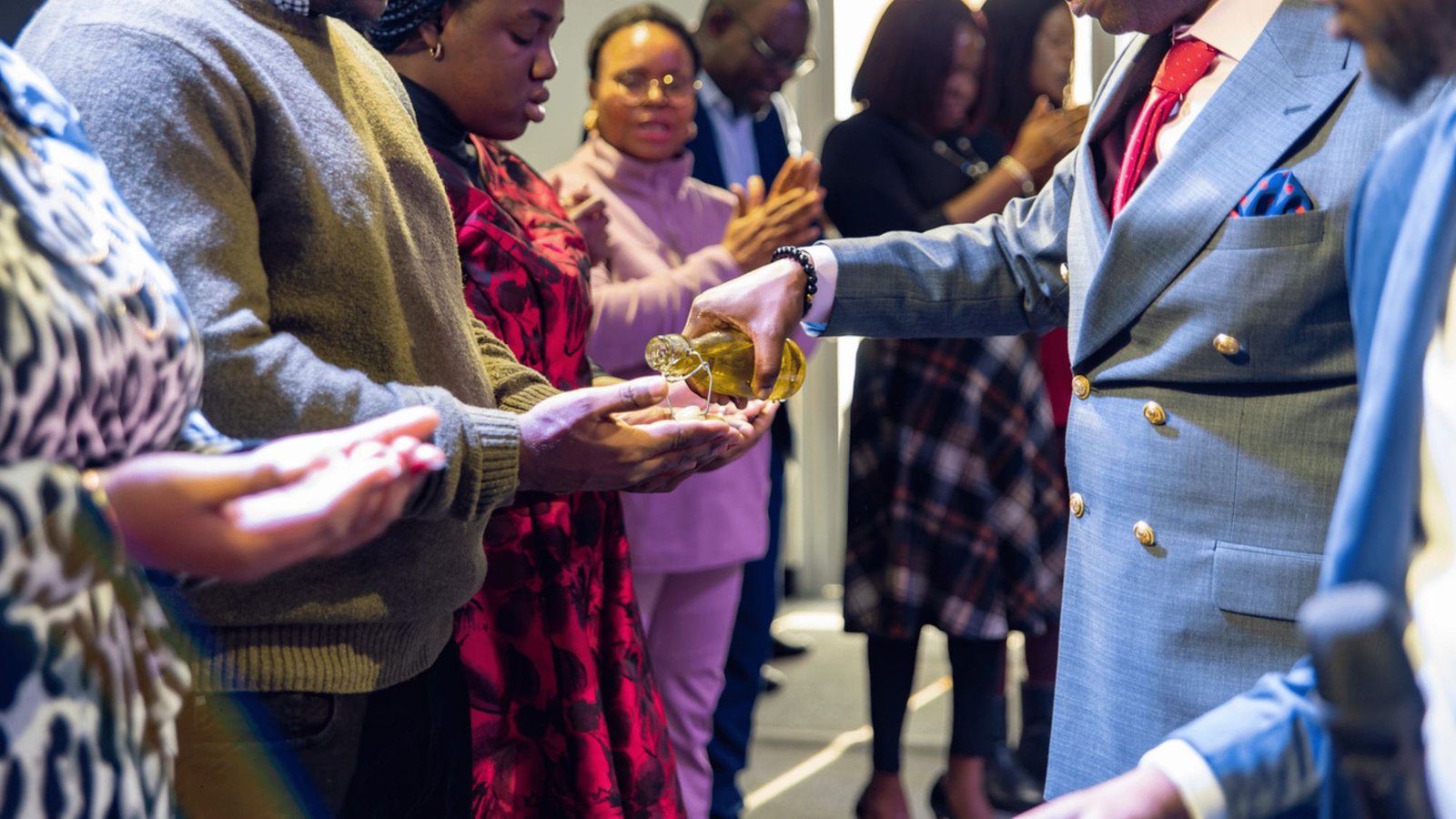 A minister anointing worshippers’ hands with oil during a service