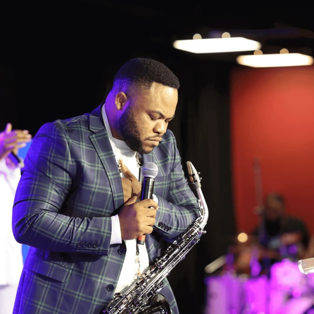 A musician holding a saxophone and singing into a microphone